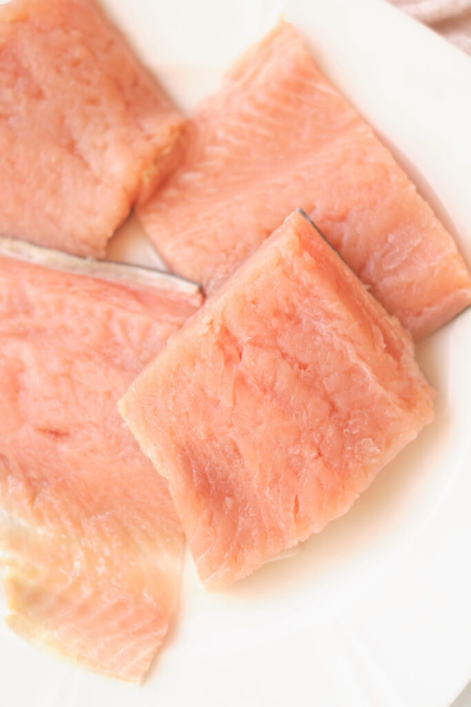 Fresh salmon fillets on a plate before baking