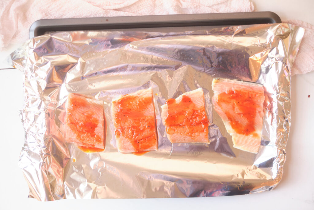 honey sriracha salmon fillets on a foil lined baking sheet before baking