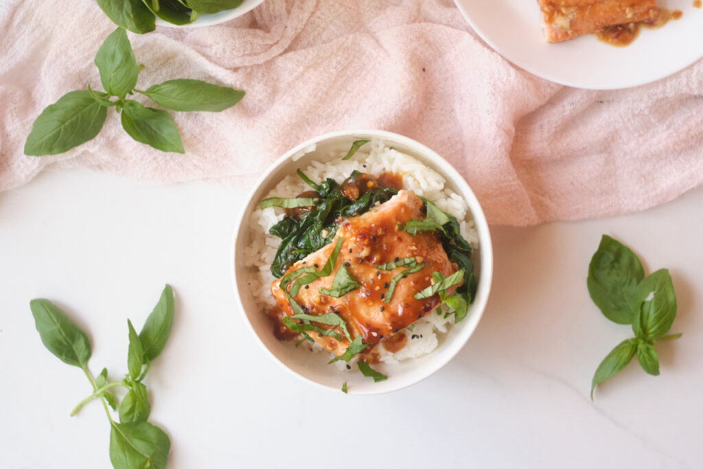 Asian rice bowl with sesame salmon, basil and spinach over rice with scattered basil around