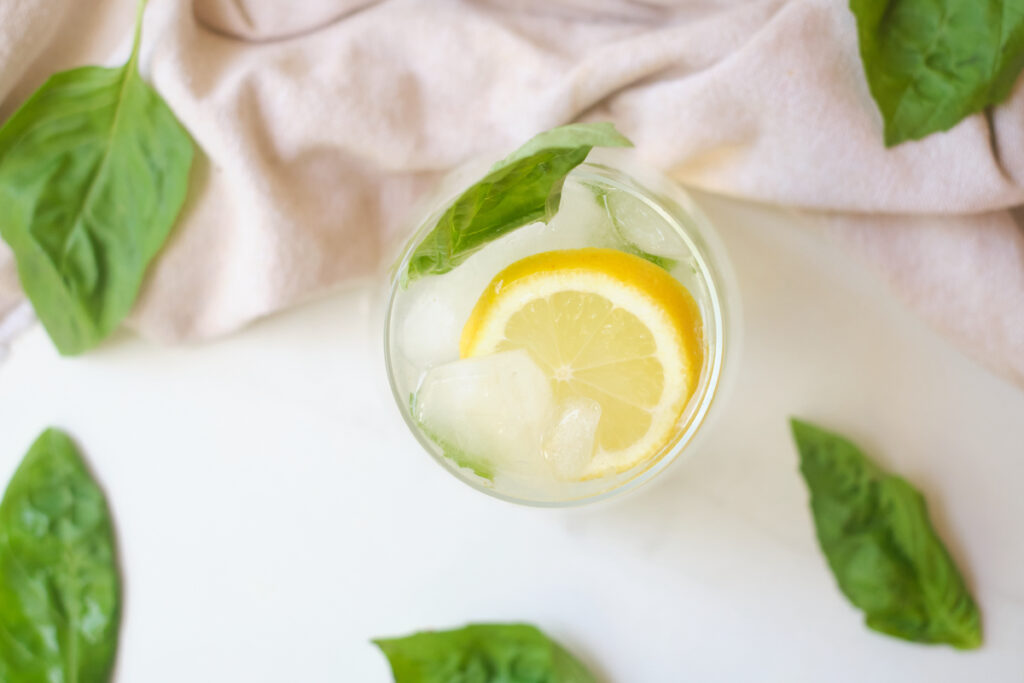 Birds eye view of coconut water lemonade with basil, with basil leaves strewn about
