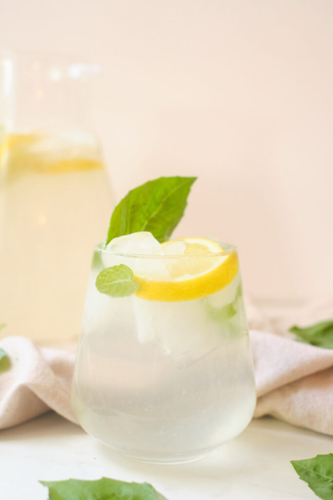 Basil coconut water lemonade in a glass garnished with lemon slice and basil