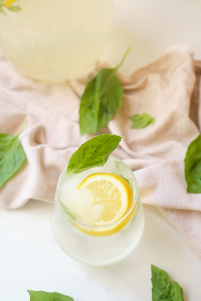 Basil coconut water lemonade in a glass garnished with lemon slice and basil