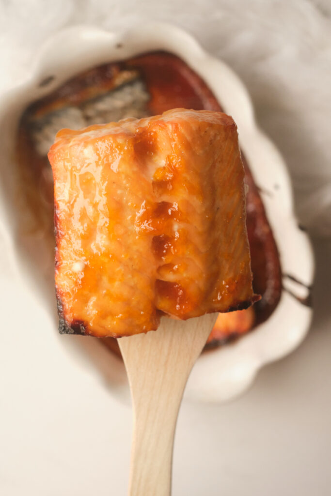 Apricot glazed salmon after coming out of the oven, on a wooden spoon