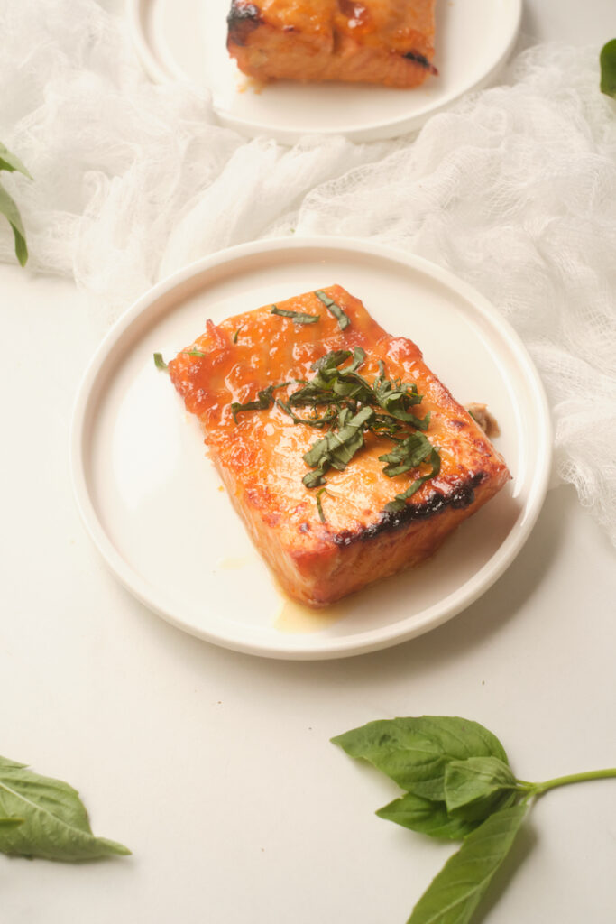 baked apricot glazed salmon with basil plated on a white plate