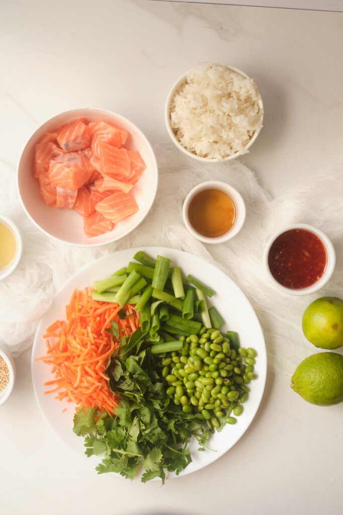 Ingredients for sweet chilli salmon rice bowls plated on a table in individual dishes