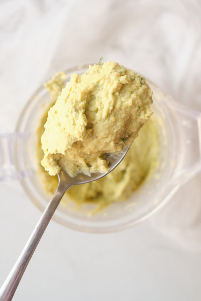 A spoonful of avocado hummus after being pulsed in a food processor