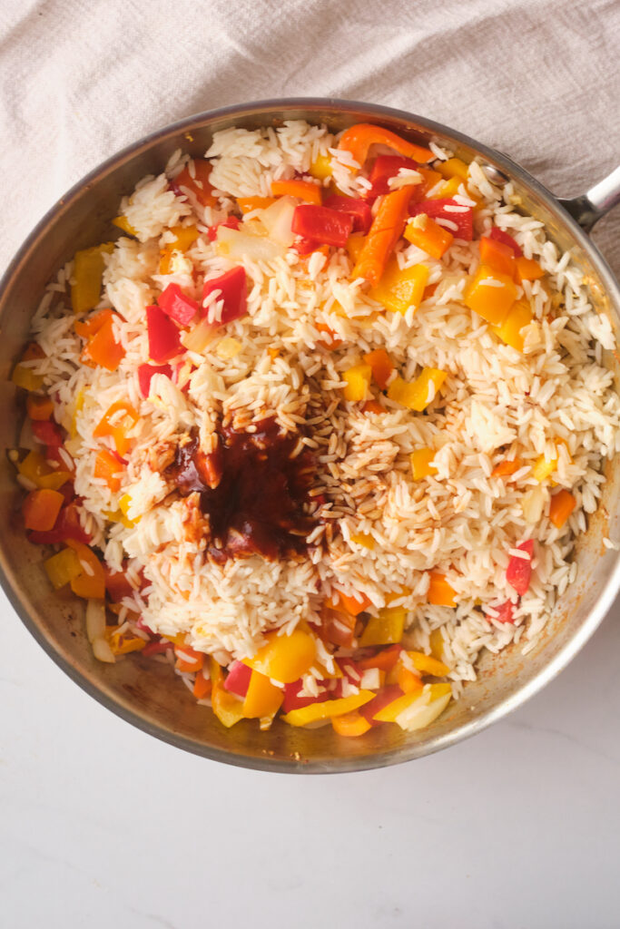rice, veggies and sauce in a pan as a step in making thai pineapple fried rice with basil