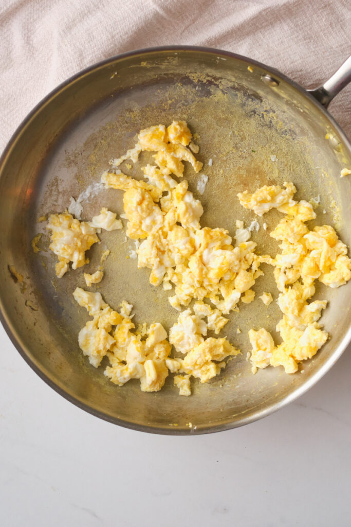 scrambled eggs being cooked in a pan