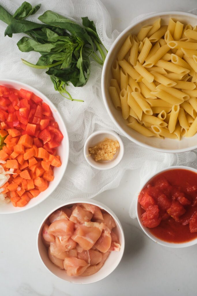 Separated ingredients to make chicken and pasta and basil soup