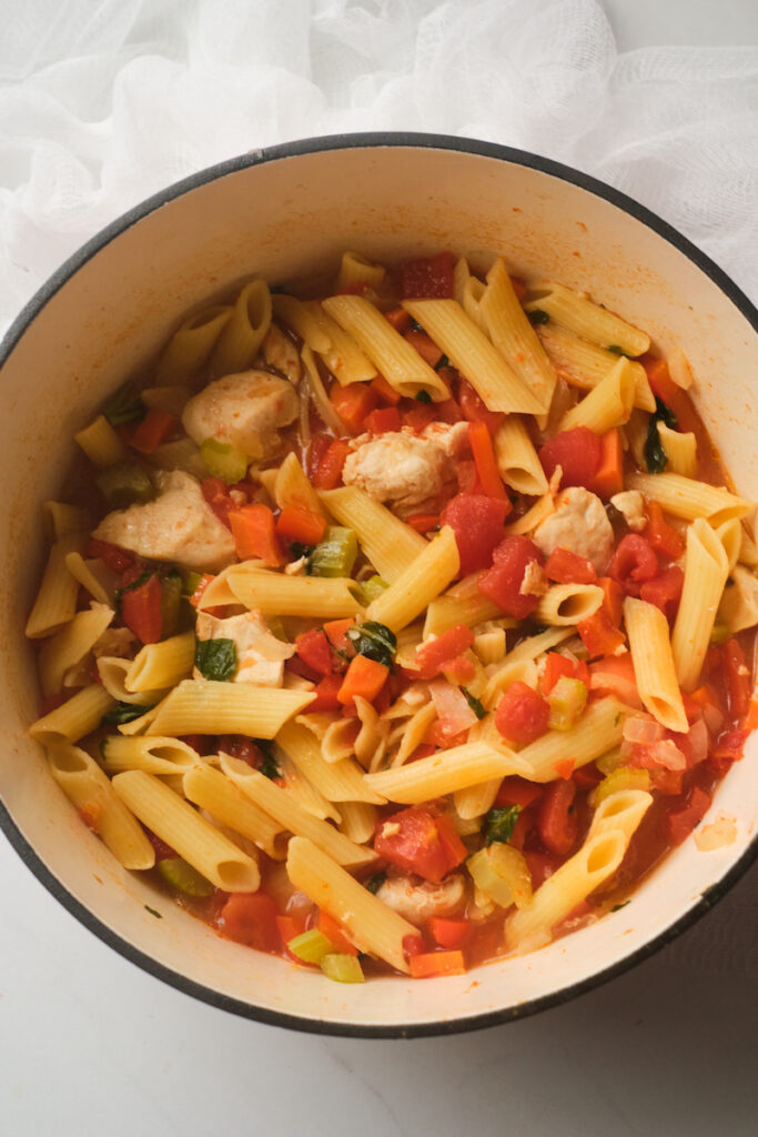 Big pot of chicken and pasta soup with basil