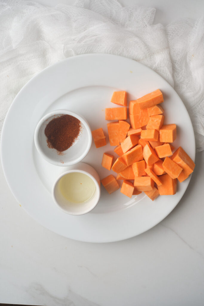 chunks of sweet potato and seasoning before cooking for an avocado sweet potato bowl