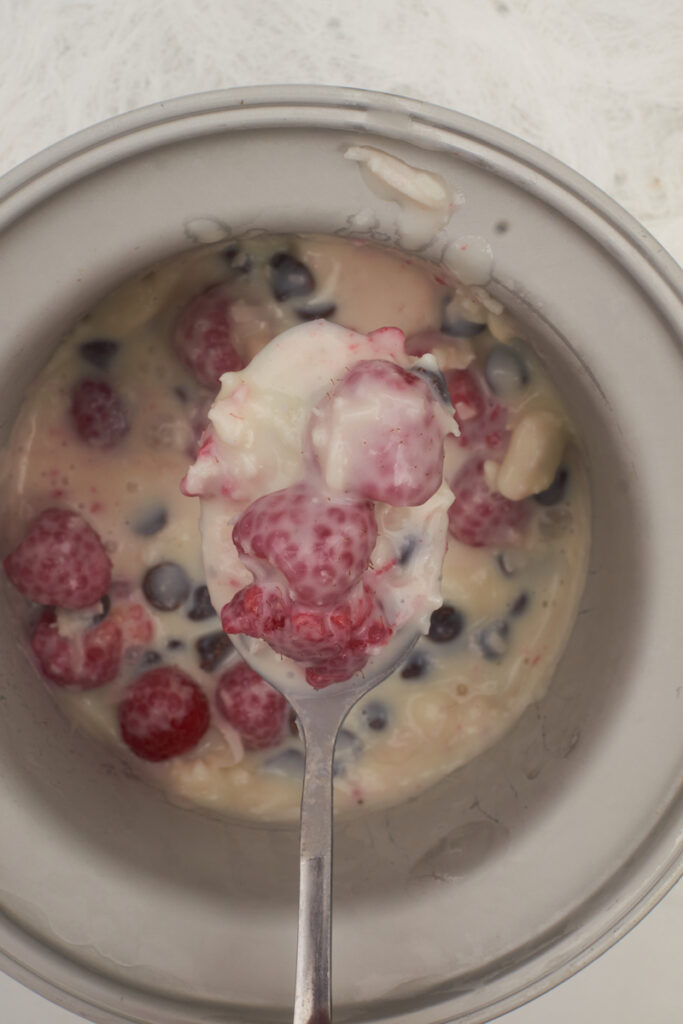 Spoon pulls some vegan raspberry dark chocolate coconut milk ice cream from an ice cream maker