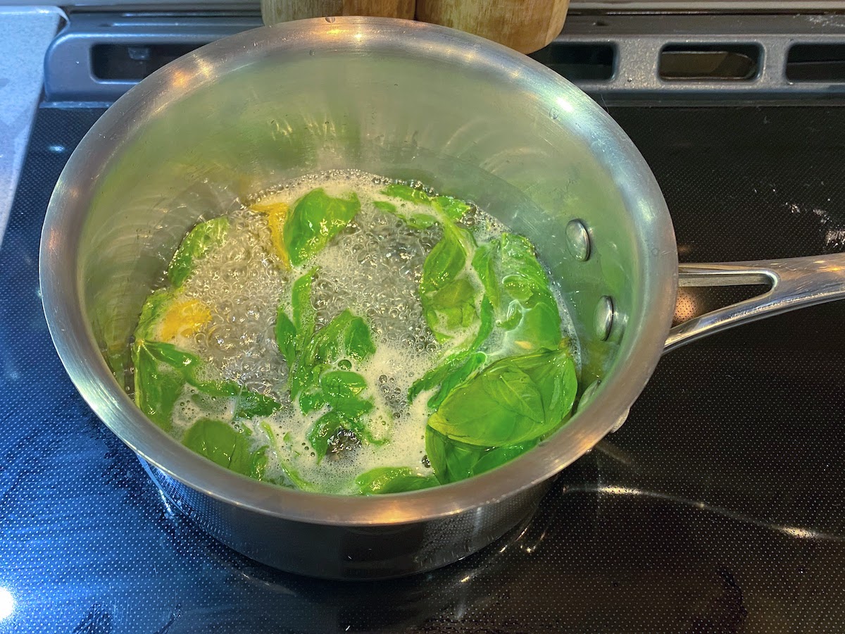 Lemon basil simple syrup boiling on a stovetop