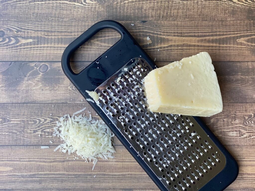 A wedge and grated pecorino cheese on a wooden table