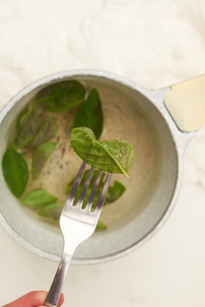 A fork with a fresh basil leaf that has been blanched in hot water and is starting to blacken