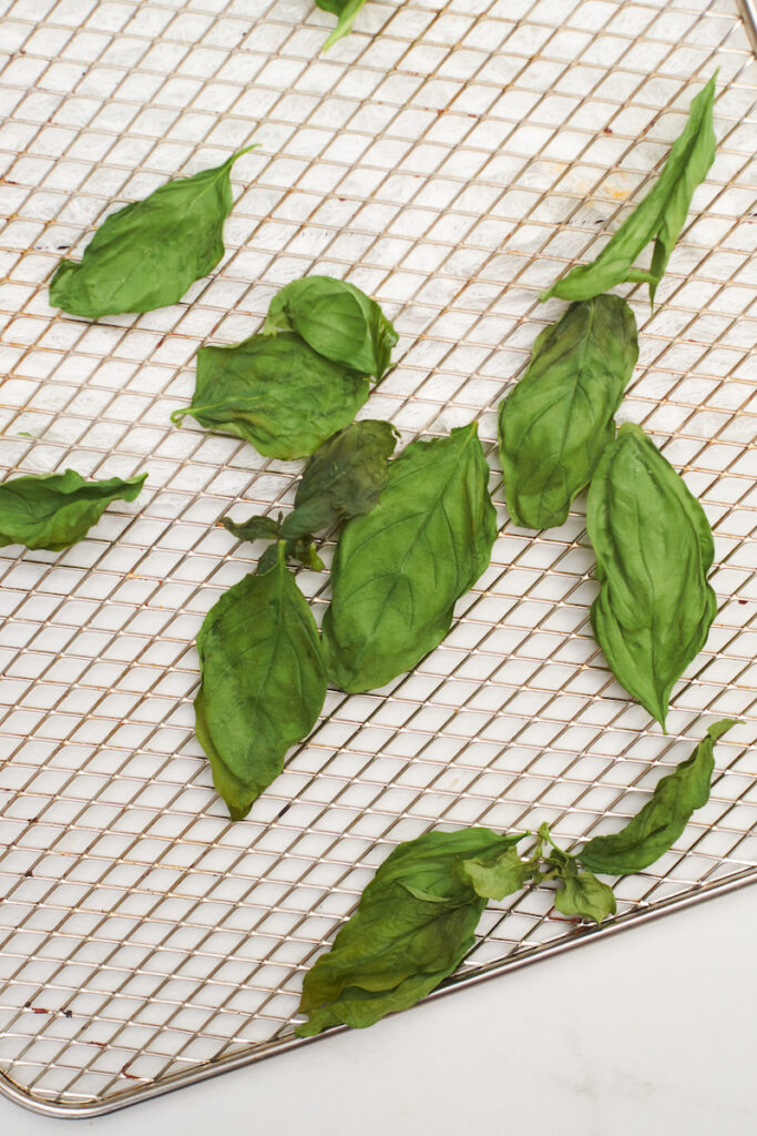 Whole dry basil leaves in an air fryer basket. Basil dried in air fryer. How to dry fresh basil in air fryer.