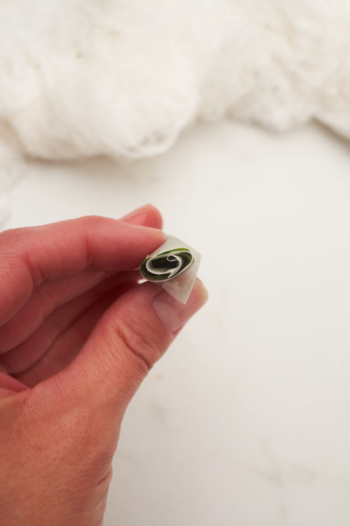 Blanched basil leaves that have been stacked and rolled into a basil cigar to freeze